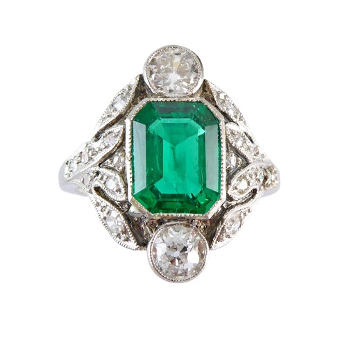 Early 20th century emerald and diamond cluster ring, c.1905, centred by an cut-corner rectangular emerald of approximately 1.20ct,